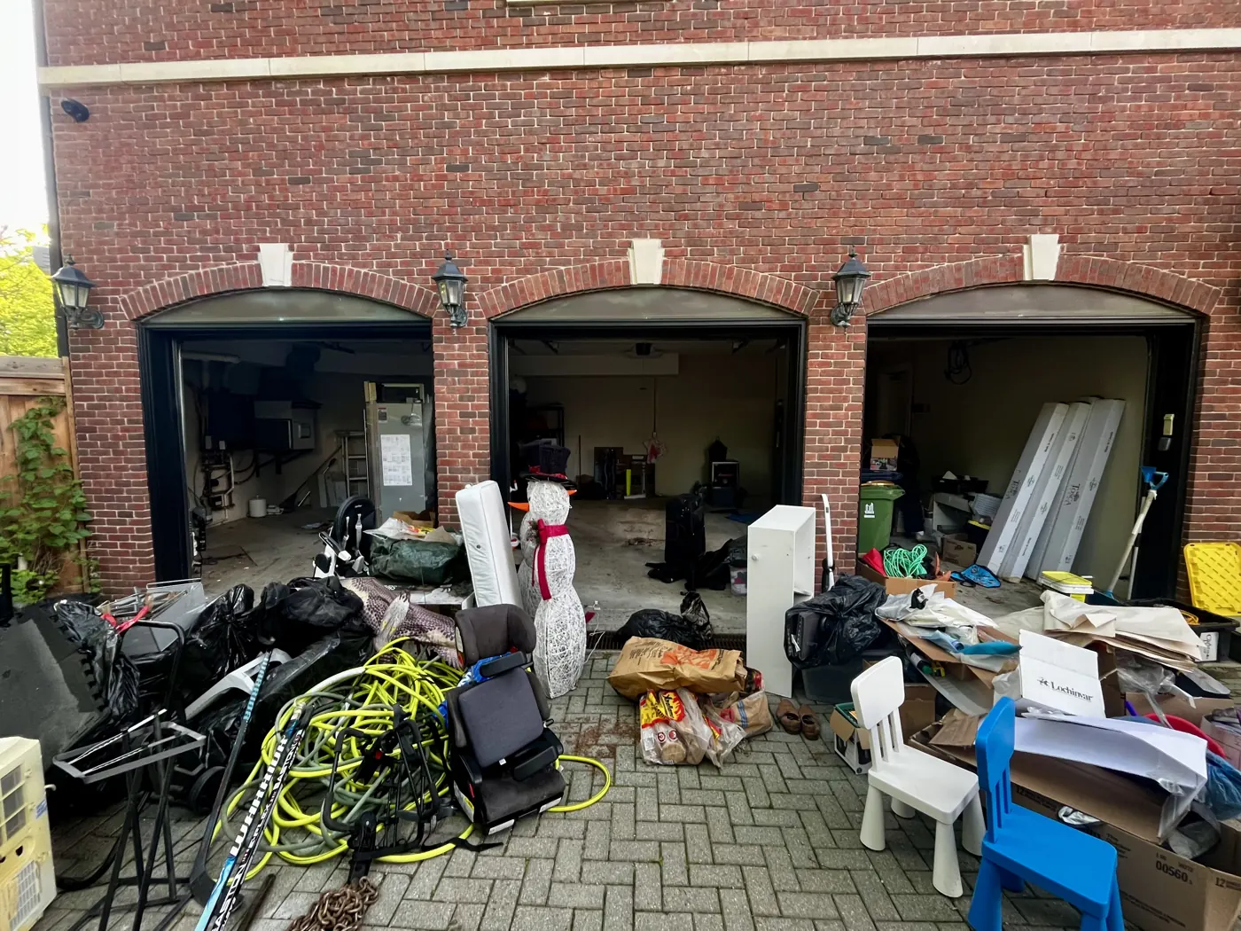 Cluttered garage and driveway before a realtor cleanout